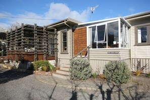 A single-story house with a wooden deck, a small front porch, and a sign that reads "The Maple Tree."