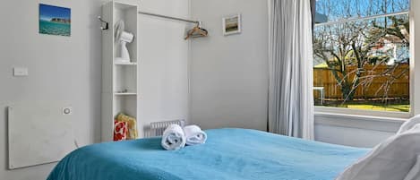 Quarto com cama, radiador, varal e janela com cortinas.