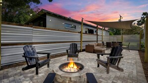 Eine Außenpatio mit Feuerstelle, Sitzgelegenheiten und Blick auf ein Haus.
