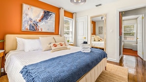 Ein Schlafzimmer mit einem großen Bett, einem Bild an der Wand und einer Tür zu einem anderen Raum.
