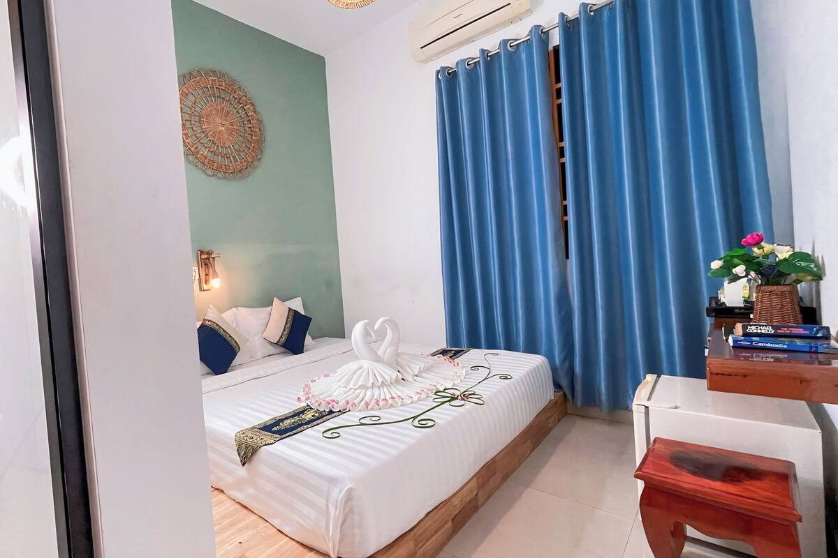 A hotel room with a bed, a desk, a chair, a toilet, and a bathroom.
