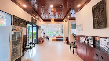 A hotel lobby with a modern design, featuring a reception desk, seating area, and a refrigerator with beverages.