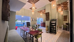 Ein Restaurant mit Terrasse, Tischen mit roten Untersetzern, hängenden Korblampen und einem Weinkühlschrank mit der Aufschrift 'BooLoom Wines'.
