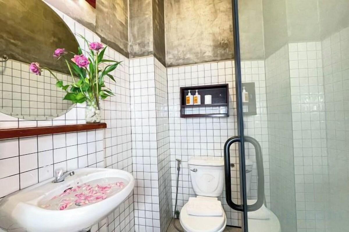 Une salle de bain avec un lavabo blanc, des toilettes et un espace douche.