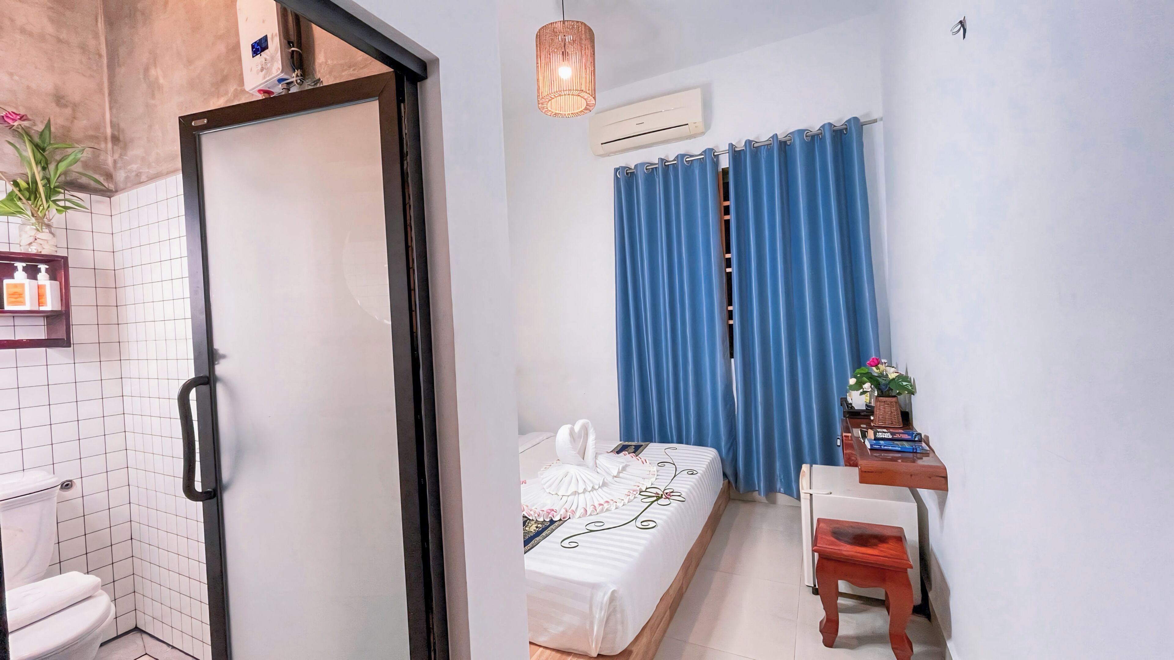 Une chambre d’hôtel de taille réduite, comprenant un lit, un petit bureau, une chaise, une salle de bain avec des toilettes et une douche.