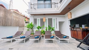 Eine Dachterrasse mit Liegestühlen, einer Bar und Topfpflanzen.