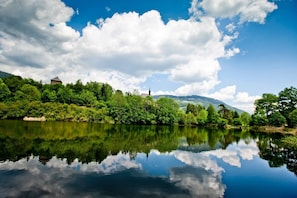 A serene river with a clear reflection of the sky and surrounding greenery.