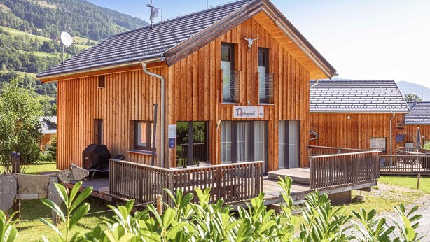 Eine Holzhütte mit einem Balkon, einem Grill und einem Schild mit der Aufschrift 'Löwengarten'.
