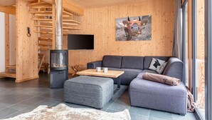 Ein modernes Interieur mit einer Holzwand, einem Kamin, einer Couch und einem großen Fenster.