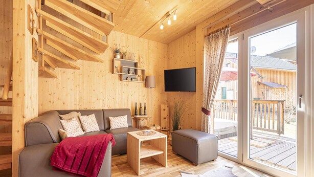 Ein Holzinnenraum mit einer Couch, einem kleinen Tisch und einem an der Wand befestigten Fernseher.