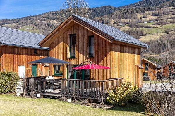 A wooden building with a balcony and outdoor seating area.