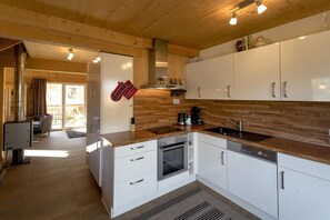 Uma cozinha moderna com armários brancos, forno de aço inoxidável e cafeteira.