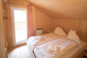 Une pièce dans une cabane en bois, avec un lit, une fenêtre et une porte.