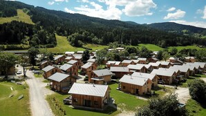 Un gruppo di chalet in legno con tetti a falde, disposti in fila, con una strada sterrata di fronte.