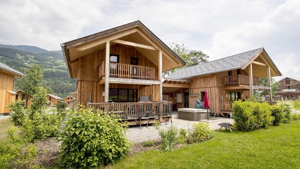Un lodge in legno con un balcone, un patio e vista sulle colline circostanti.