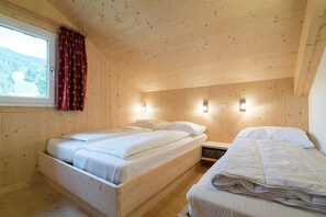 A wooden cabin bedroom with two beds, a window with curtains, and wall-mounted lights. - Chalet with e-charging station (Kreischberg Murau)