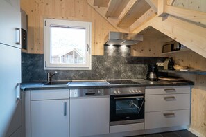 Una cocina moderna con horno empotrado, campana extractora de acero inoxidable y ventana sobre el fregadero.