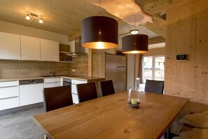 Enjoy meals in the kitchen with an oven and stainless steel dishwasher, surrounded by a wooden table and pendant lights.