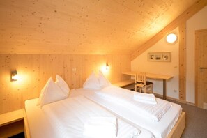 Une chambre avec deux lits, des murs en bois, un bureau et une chaise.