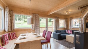 Un intérieur en bois avec une table à manger dressée pour quatre personnes, un canapé et une cheminée.