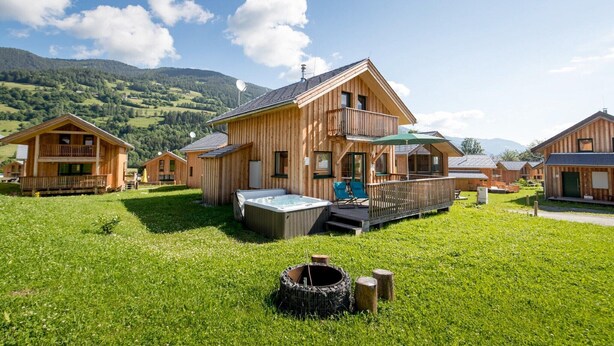 Une cabane en bois avec un jacuzzi, une terrasse et une cour gazonnée.