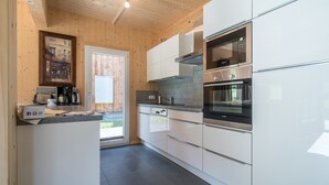 Une cuisine moderne avec des armoires blanches, des appareils en acier inoxydable et un plafond en bois.