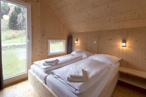 Une pièce de cabane en bois avec deux lits, une fenêtre et une porte.