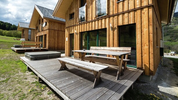 Une cabane en bois dotée d’une terrasse, d’une table de pique-nique et de bancs.