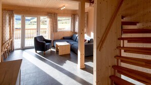 A wooden interior with a sofa, armchair, and a small table.