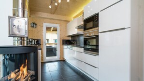 Una cocina moderna con estufa de leña, electrodomésticos de acero inoxidable y vistas al exterior.