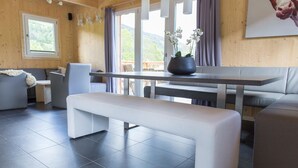 Un interior moderno con un banco, sofás grises, una mesa de comedor y una planta en maceta.