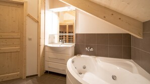 Un baño con techo de madera, bañera, lavamanos y espejo.