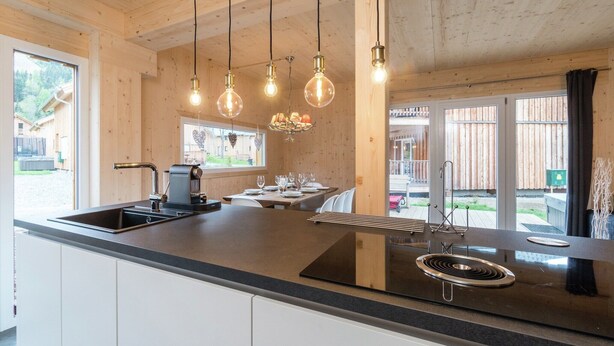 Una cocina moderna con una isla grande, electrodomésticos de acero inoxidable y lámparas colgantes.