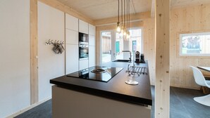 Una cocina moderna con una isla central, electrodomésticos de acero inoxidable e iluminación colgante.