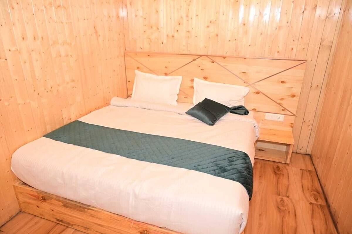 A wooden-paneled room with a bed, pillows, and a quilted blanket.