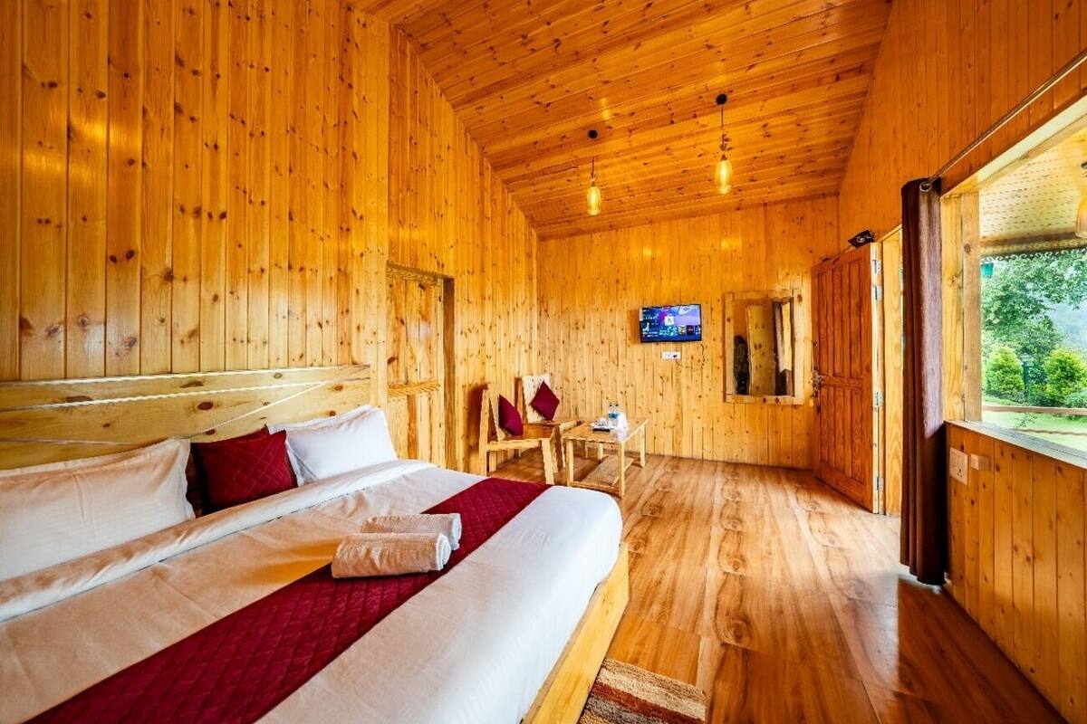 A wooden room with a bed, a TV, and a window.
