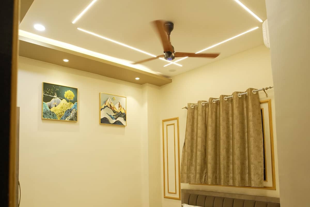 Un dormitorio con cama, ventilador de techo, obras de arte y cortinas.