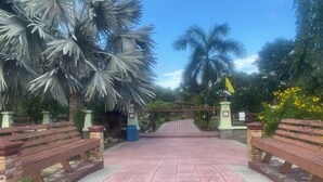 A paved pathway leading to a gated entrance with benches on either side. - House for rent in Hua Hin for wintering 180 days visa (Hua Hin)