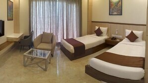 A hotel room with two beds, a TV, a coffee table, and a chair.