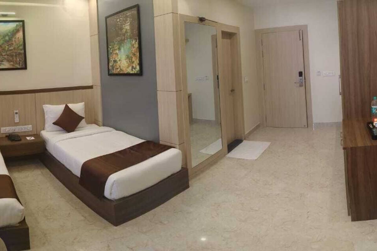 A hotel room with two beds, a desk, a mirror, and a wardrobe.