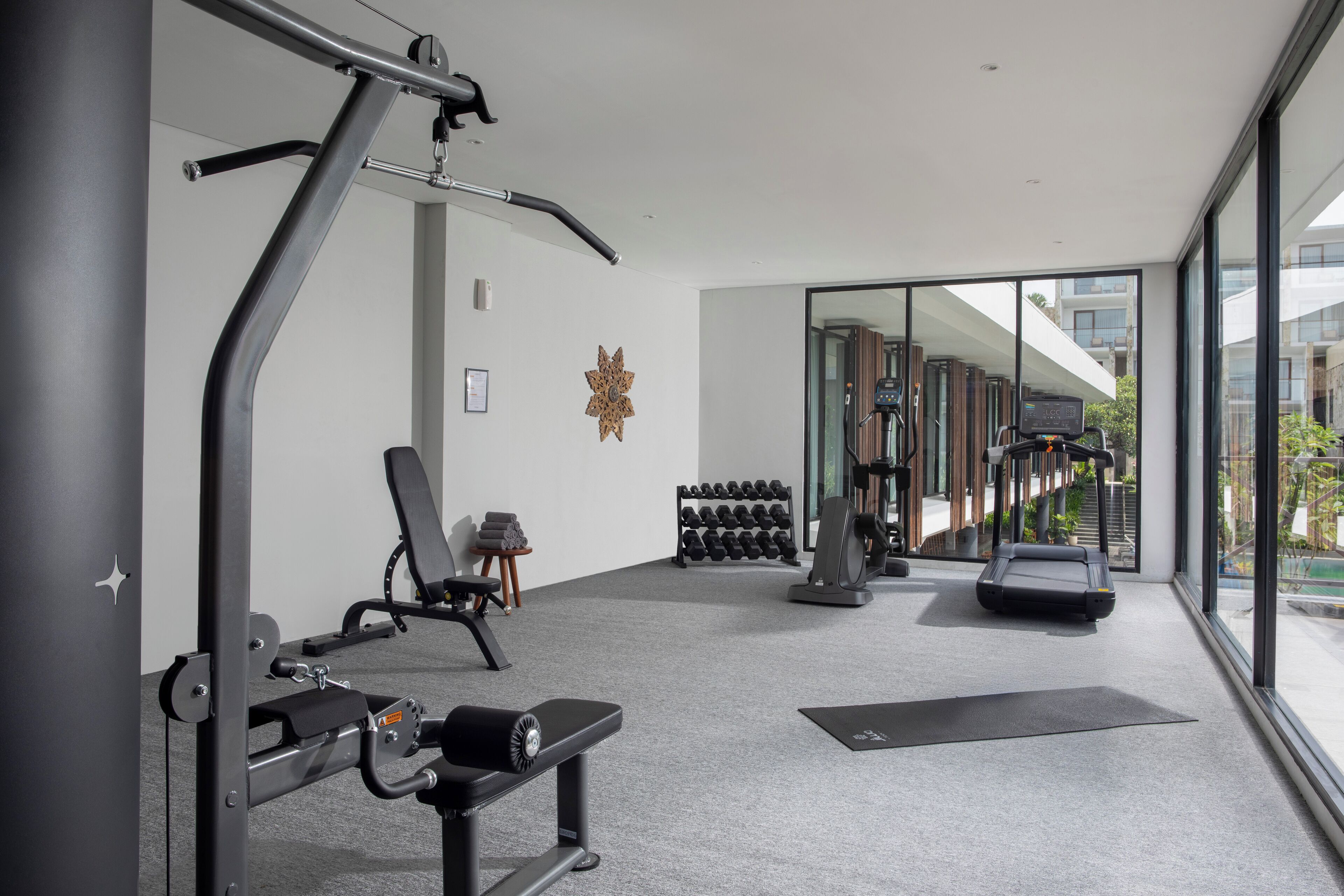 Un gimnasio moderno con equipo de ejercicio, una cinta de correr y un estante de mancuernas en la pared.