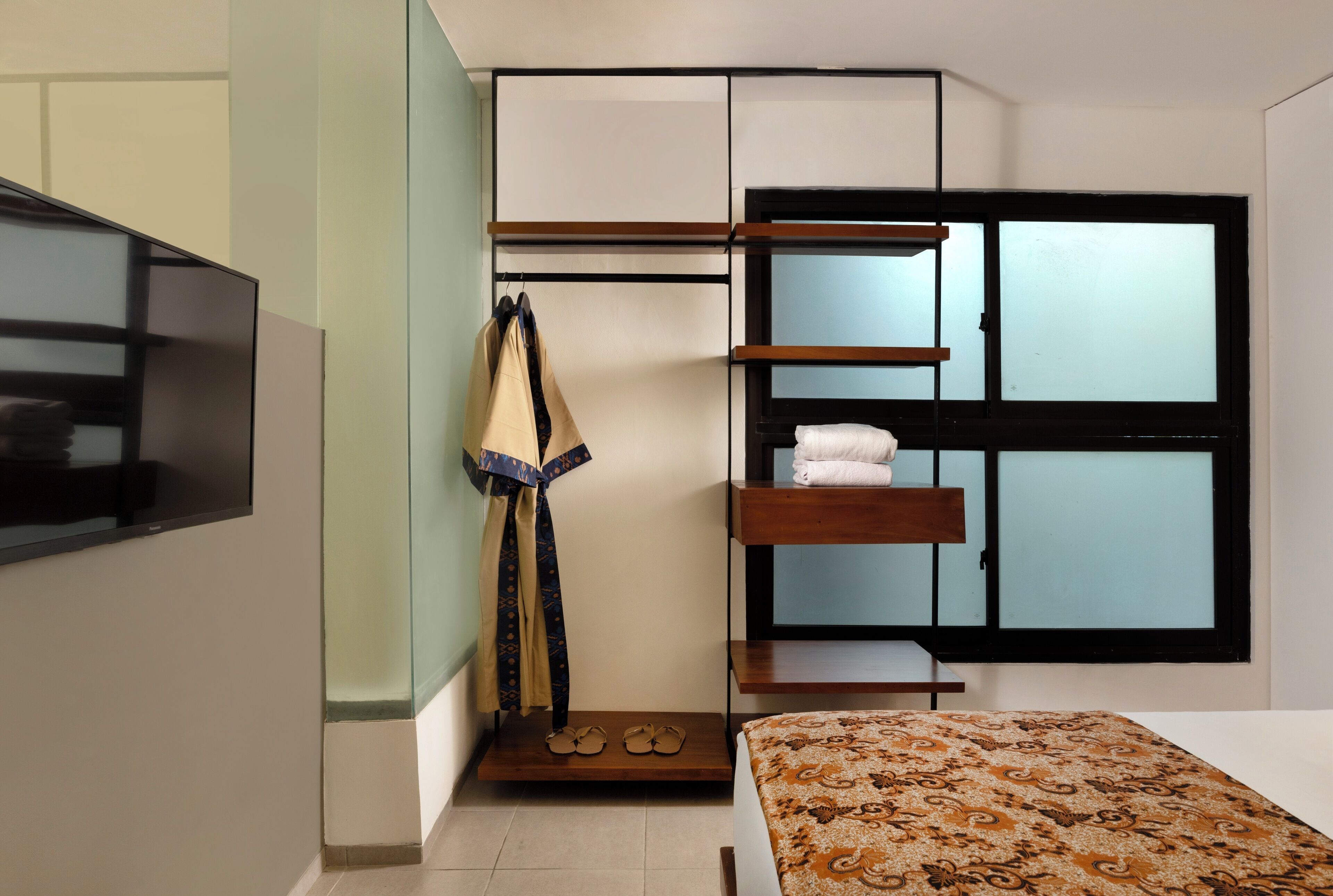 A bedroom with a bunk bed, a TV mounted on the wall, a wardrobe with a mirror, and a window with blinds.