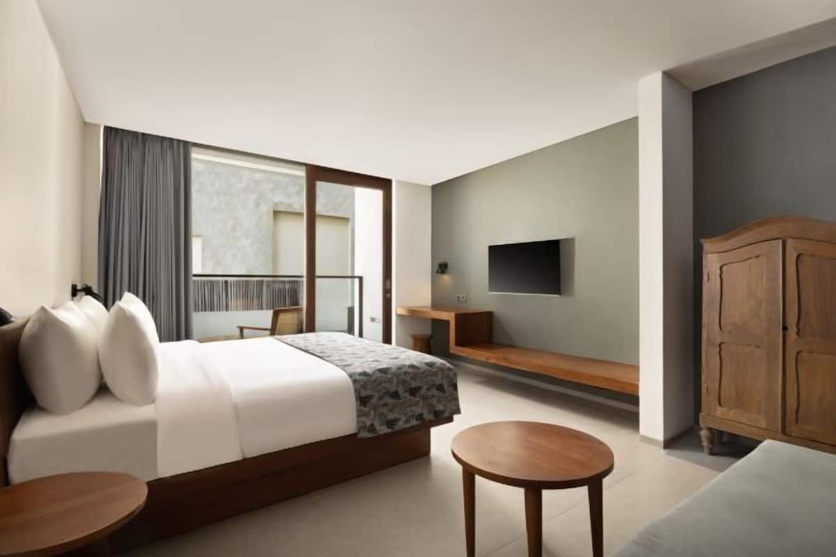 A modern hotel room with a large bed, a TV, a wooden cabinet, and a small table.
