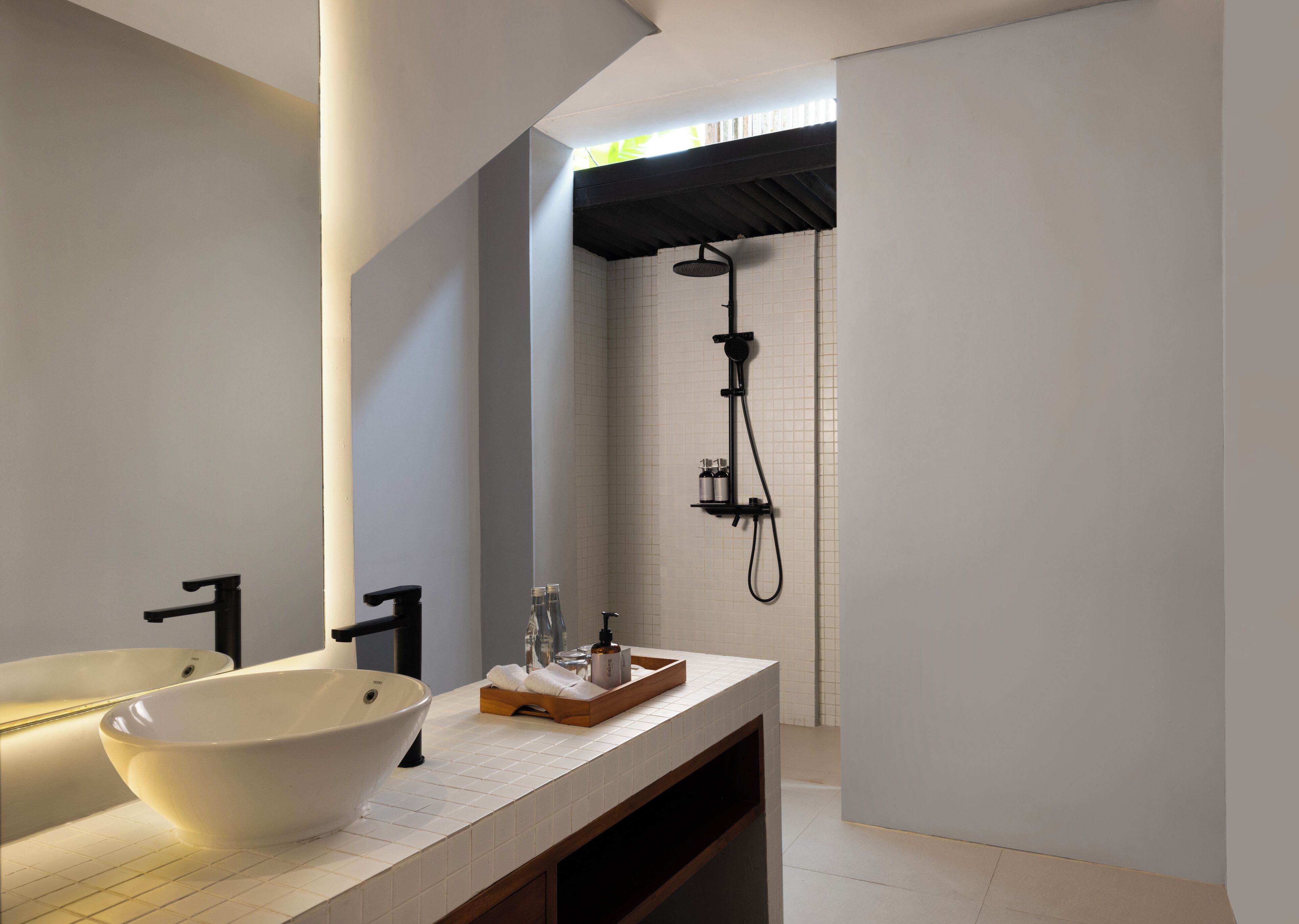A modern bathroom with a white sink, black faucet, and a handheld showerhead.