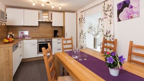 A modern kitchen with white cabinets, a wooden countertop, and a dining area with a purple tablecloth. - Cozy vacation apartment and perfect base in the heart of Tyrol (Inzing)