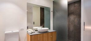 Bathroom features a toilet, vanity with drawers, and a large mirror.