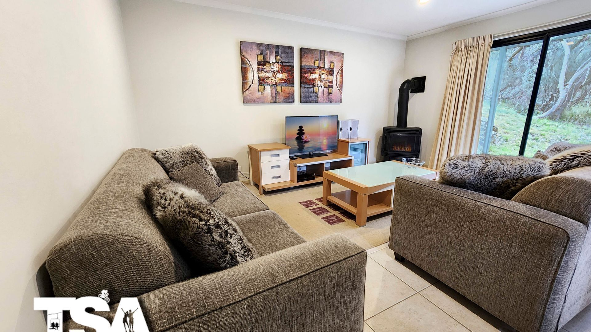 A living room with a sofa set, a TV, a wooden coffee table, and a fireplace.
