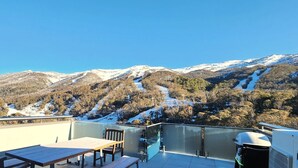 A terrace with a table and chairs, overlooking a snow-covered mountain range. - The Peak Penthouse 8 (Central Village)
