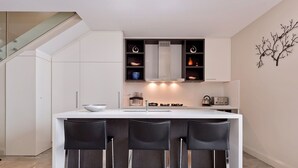 A modern kitchen with a central island, bar stools, and built-in cabinets.
