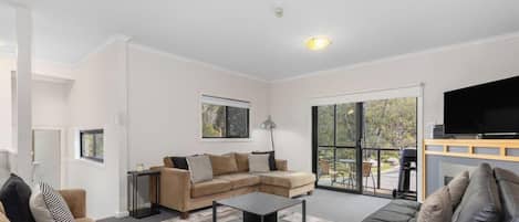 A living room with a sofa, a coffee table, a TV, and a large window.